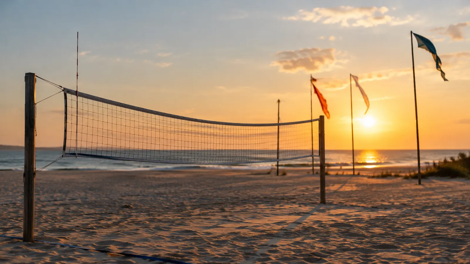 A volleyball net standing on the sand with the top edge sagging slightly in the middle